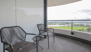 Un balcón con dos sillas y vistas a un lago y campos.