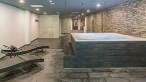 A spa area with a hot tub, lounge chairs, and a stone wall. - Spacious Family Stay | Wellness Access & Outdoor Adventure | Valley, Forest Site (Wageningen)