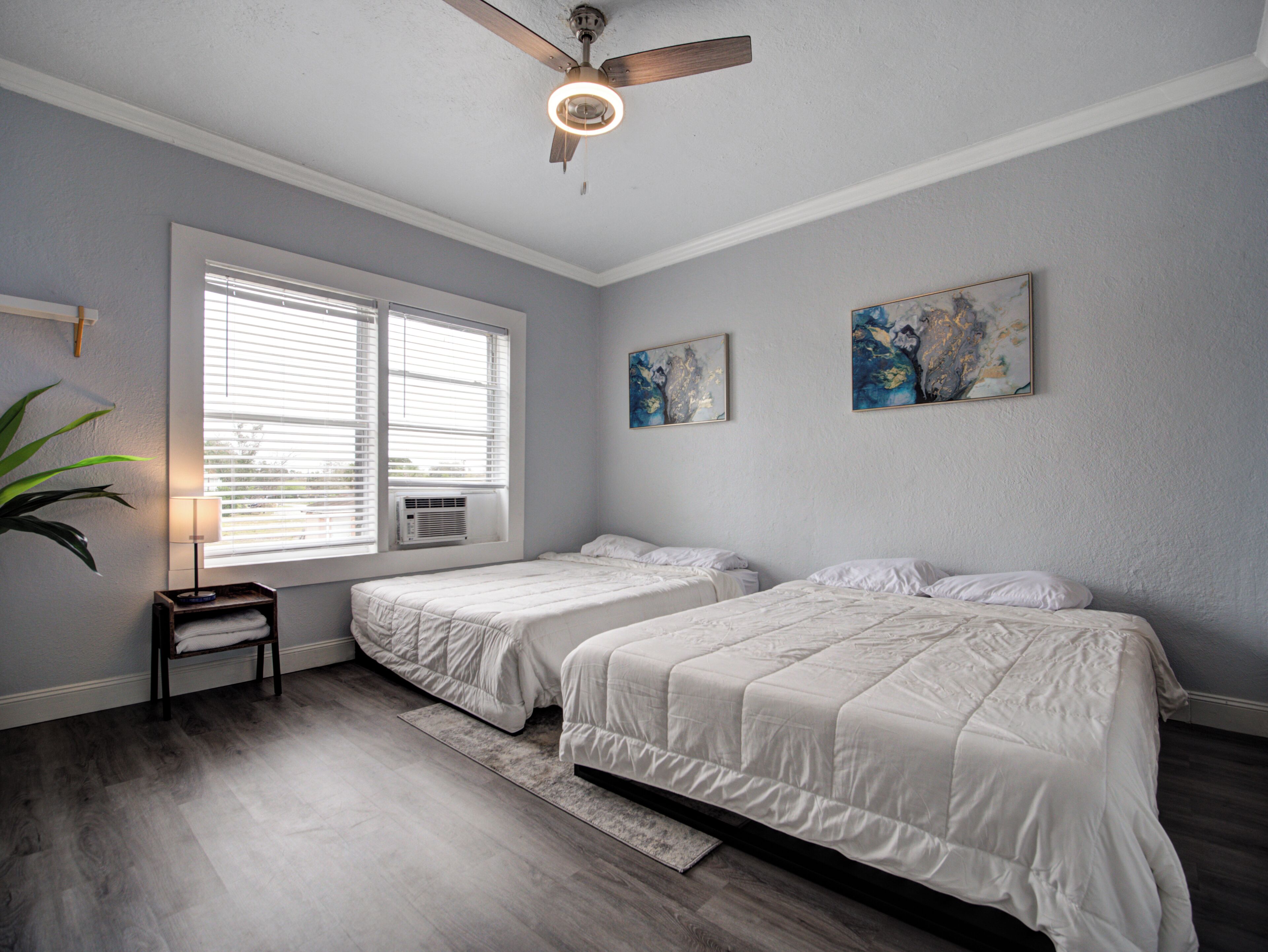 Ein Schlafzimmer mit zwei Betten, einem Deckenventilator und Kunstwerken an den Wänden.