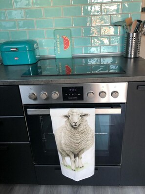 A kitchen with a stainless steel oven, a digital clock, and a towel with a sheep design hanging from the oven handle. - Familienurlaub nahe Europa-Park & Rulantica mit Garten, Trampolin & Balkon (Herbolzheim)