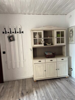 A room with a white wall, a wooden floor, a white cabinet with glass doors, and a wall-mounted coat rack. - Familienurlaub nahe Europa-Park & Rulantica mit Garten, Trampolin & Balkon (Herbolzheim)