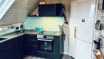 Eine kompakte Küche mit Einbauofen, einem weißen Kühlschrank und einem Fenster über der Spüle.