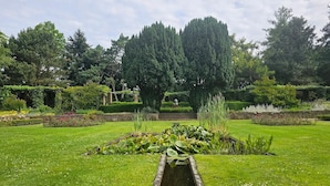 Un jardin avec un bassin central, entouré de pelouse bien entretenue et de diverses plantes.