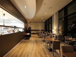 Un restaurant modern amb sòcols de fusta, grans finestres i diverses opcions de seients.
