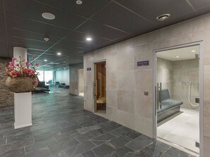 Un hall modern amb terra de pedra, una recepció, una zona de dutxes i un arranjament floral penjat a la paret.