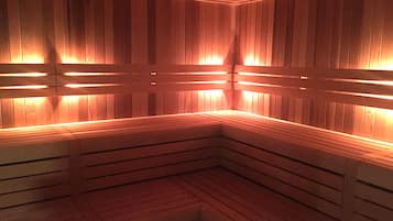 A sauna with wooden benches and walls, illuminated by warm lighting.