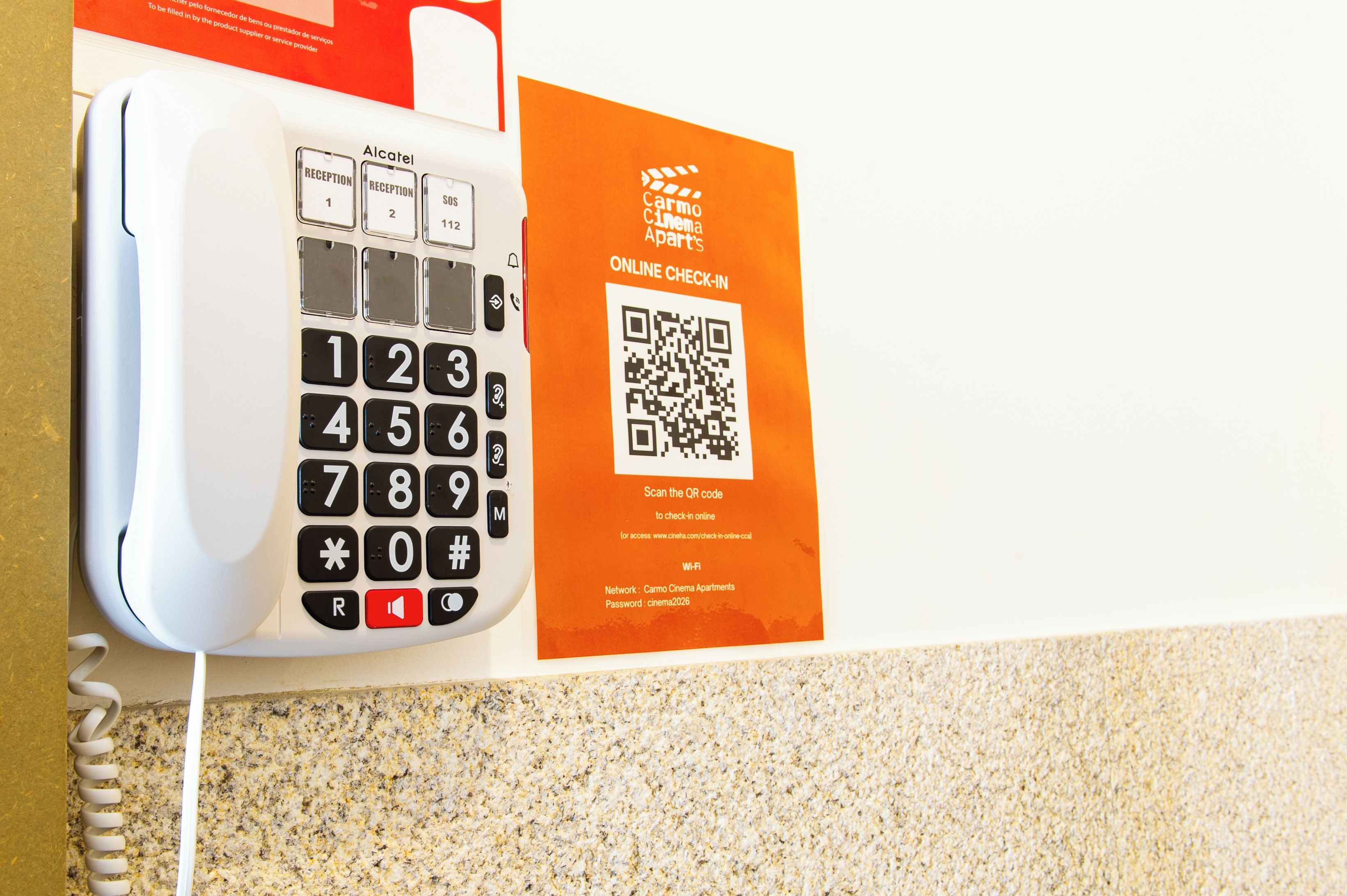 En hvid telefon med en QR-kode og et skilt til online check-in ved Carmo Cinema Apartments.