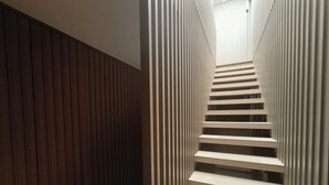 A modern staircase with a wooden wall on one side and a white, striped wall on the other. - Carmo Cinema Apartments (Porto)