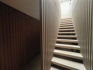 Eine moderne Treppe, an einer Seite eine Holzverkleidung und an der anderen eine weiße, gestreifte Wand.