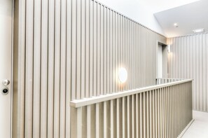 A modern interior with vertical paneling, a white railing, and a round light fixture. - Carmo Cinema Apartments (Porto)