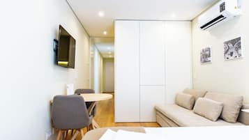 Une chambre d’hôtel moderne équipée d’un lit, d’un bureau, d’une chaise, d’un téléviseur à écran plat fixé au mur et d’un appareil de climatisation.