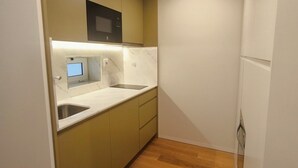 A compact kitchen with a microwave, a sink, and a refrigerator. - Carmo Cinema Apartments (Porto)