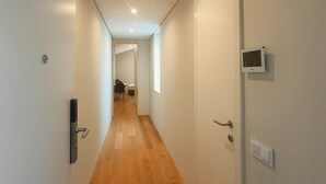 A hallway with wooden flooring, white walls, and doors on both sides. - Carmo Cinema Apartments (Porto)