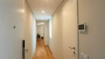 Un corridoio con pavimento in legno, pareti bianche e porte su entrambi i lati.