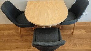 A round wooden table with four grey upholstered chairs. - Carmo Cinema Apartments (Porto)