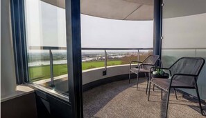 A balcony with a view of a river and fields, a chair, and a small table. - Panoramic Nature Getaway w/Relaxing Spa |Near Forest Reserves & Local Landmarks (Wageningen)