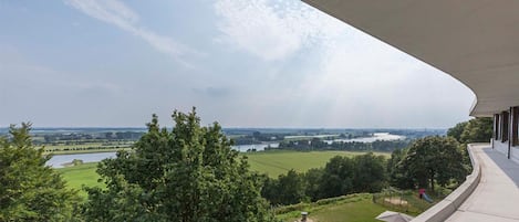 A balcony with a view of a lake and fields.