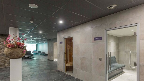 A modern lobby with a stone floor, a reception desk, a shower area, and a wall-mounted flower arrangement. - Relaxing Retreat w/Sauna, Gym & Dining | Arboretum Belmonte, De Hoge Veluwe (Wageningen)