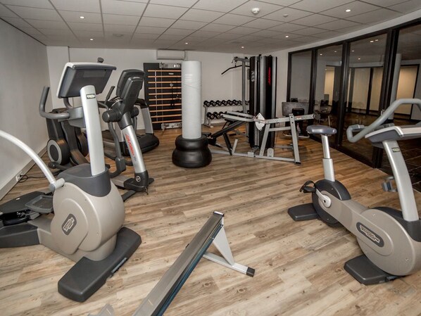 Un gimnasio con diversos equipos de ejercicio, incluyendo cintas de correr, elípticas y máquinas de pesas.