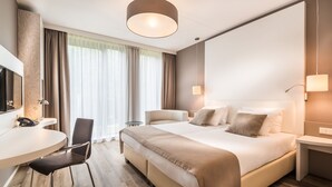 A hotel room with a bed, bedside tables, a desk with a chair, a TV, and a large window with curtains. - Breathtaking Stay w/Spa & Scenic Surroundings | Local Dining & Nature Spots (Wageningen)