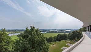 A balcony with a view of a lake and fields.