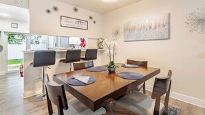 Een eethoek met een houten tafel, zwarte stoelen en een decoratief wandobject.