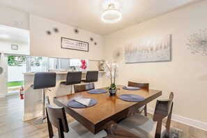 A dining area with a wooden table, black chairs, and a decorative wall piece. - Cozy Retreat | Beach, Airport & Cruise Port (Fort Lauderdale)