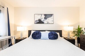 A hotel room with a bed, two bedside lamps, a desk, and a potted plant. - Cozy Retreat | Beach, Airport & Cruise Port (Fort Lauderdale)
