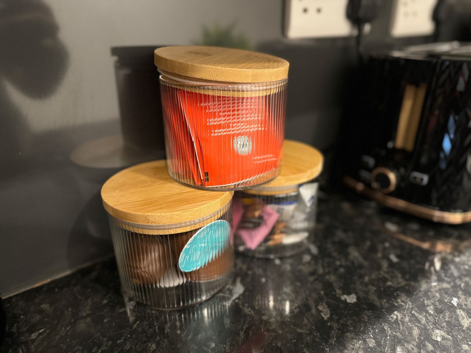 Three cylindrical containers with lids on a kitchen counter.