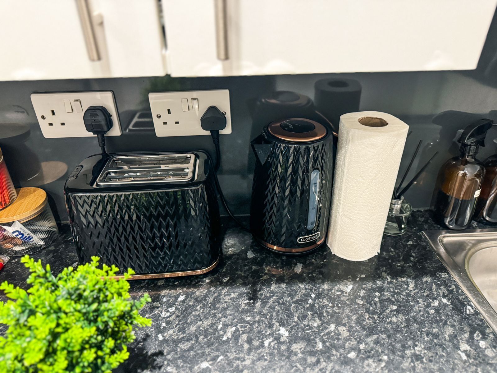 A kitchen counter with a toaster, a kettle, and a roll of paper towels.