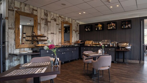Un restaurant moderne avec un mur en bois, un espace bar et un aménagement pour accueillir les clients.