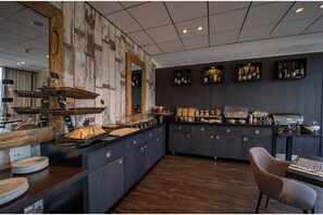 A modern kitchen with a rustic wooden wall, a buffet setup, and a coffee station.