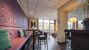 Un espace bar moderne, doté d’un coin salon, d’un comptoir et offrant une vue dégagée grâce à de grandes fenêtres.