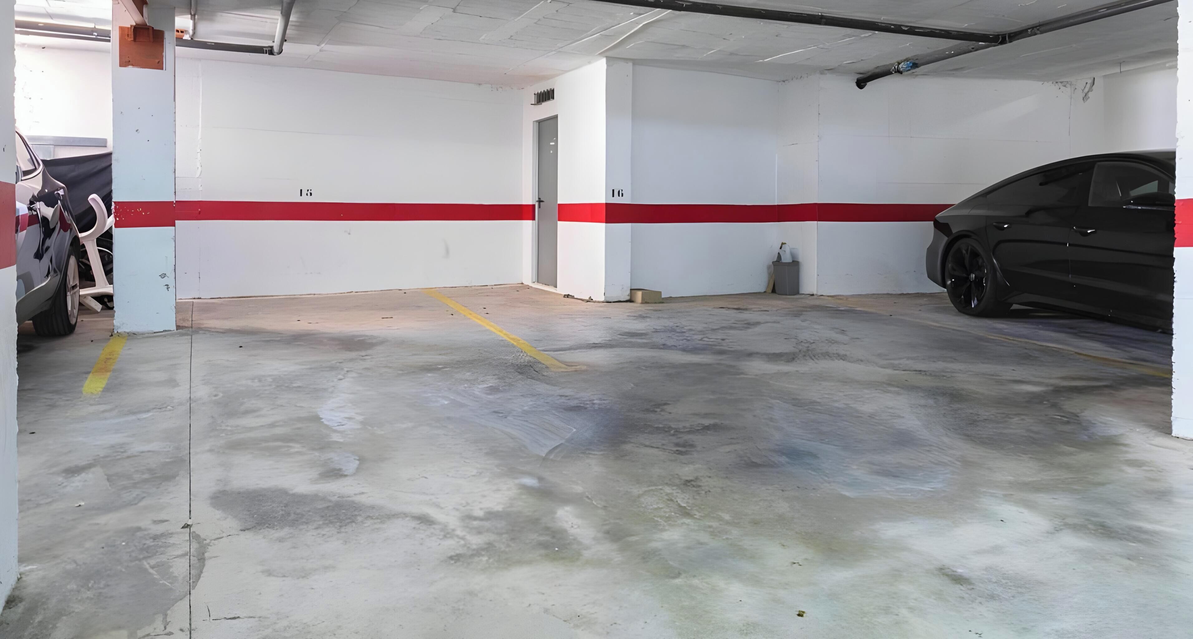 Eine Tiefgarage mit Betonböden, weißen Wänden und einem roten Streifen.