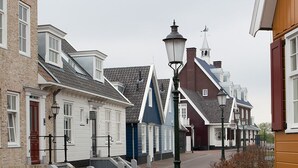 Una calle con arquitectura europea tradicional, que incluye un campanario de iglesia y un farol.