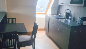 Una cocina compacta con una mesa y sillas, estufa integrada y un ventanal que proporciona luz natural.