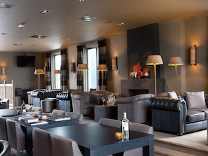 A modern living room with leather sofas, a coffee table, and wall-mounted lamps.