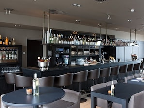 A modern bar area with a long counter, multiple seating options, and a variety of bottles and glasses on display. - Perfect Harbor Stay w/Onsite Dining | Near Huizen Attractions & Nature Reserves (Huizen)