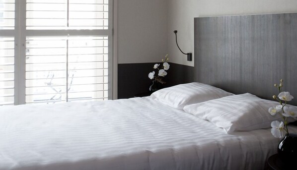 A neatly made bed with white linens, a dark headboard, and a vase with white flowers on a bedside table. - Spacious Suite w/Balcony | Breathtaking Reserves, Cultural Sights & Local Dining (Huizen)