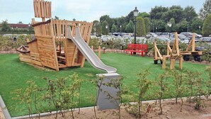 Ein Spielplatz mit einer Holzrutsche und Klettergerüsten.
