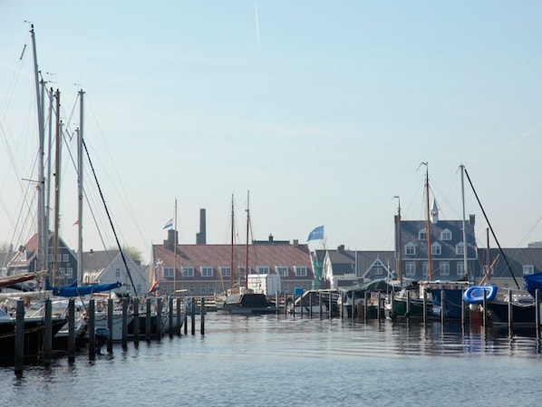 A marina with boats docked at wooden piers, a clear sky, and buildings in the background. - Serene Stay w/Oniste Dining Near Huizer Museum, Nature Reserve & Cultural Sites (Huizen)