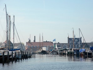 A marina with boats docked at wooden piers, a clear sky, and buildings in the background. - 2 Relaxing Haven Near Naarderbos Trails, Nature Reserve & Cultural Attractions (Huizen)