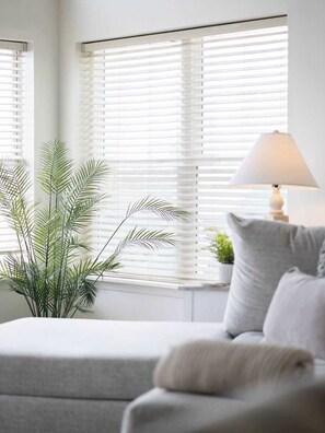 A room with a sofa, a lamp, and a plant near a window with blinds. - Palencia by the Sea - Ocean & Lighthouse Views (St. Augustine)