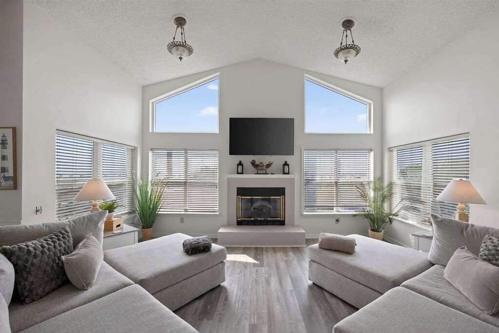 A spacious living room with a fireplace, two sofas, and large windows.