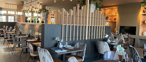 A modern restaurant with wooden decor, multiple dining tables, and chairs.