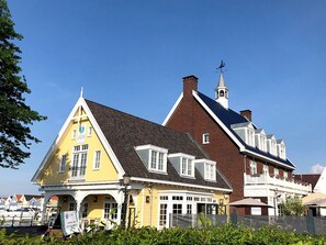 Ein gelbes Gebäude im traditionellen Baustil, mit einem markanten Turm und Wetterfahne.