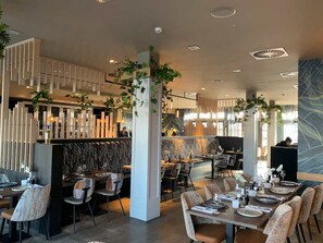 Ein modernes Restaurant-Interieur mit hohen Tischen, Stühlen und vertikalen Gärten.