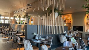 Een modern restaurant met houten inrichting, meerdere eettafels en stoelen.
