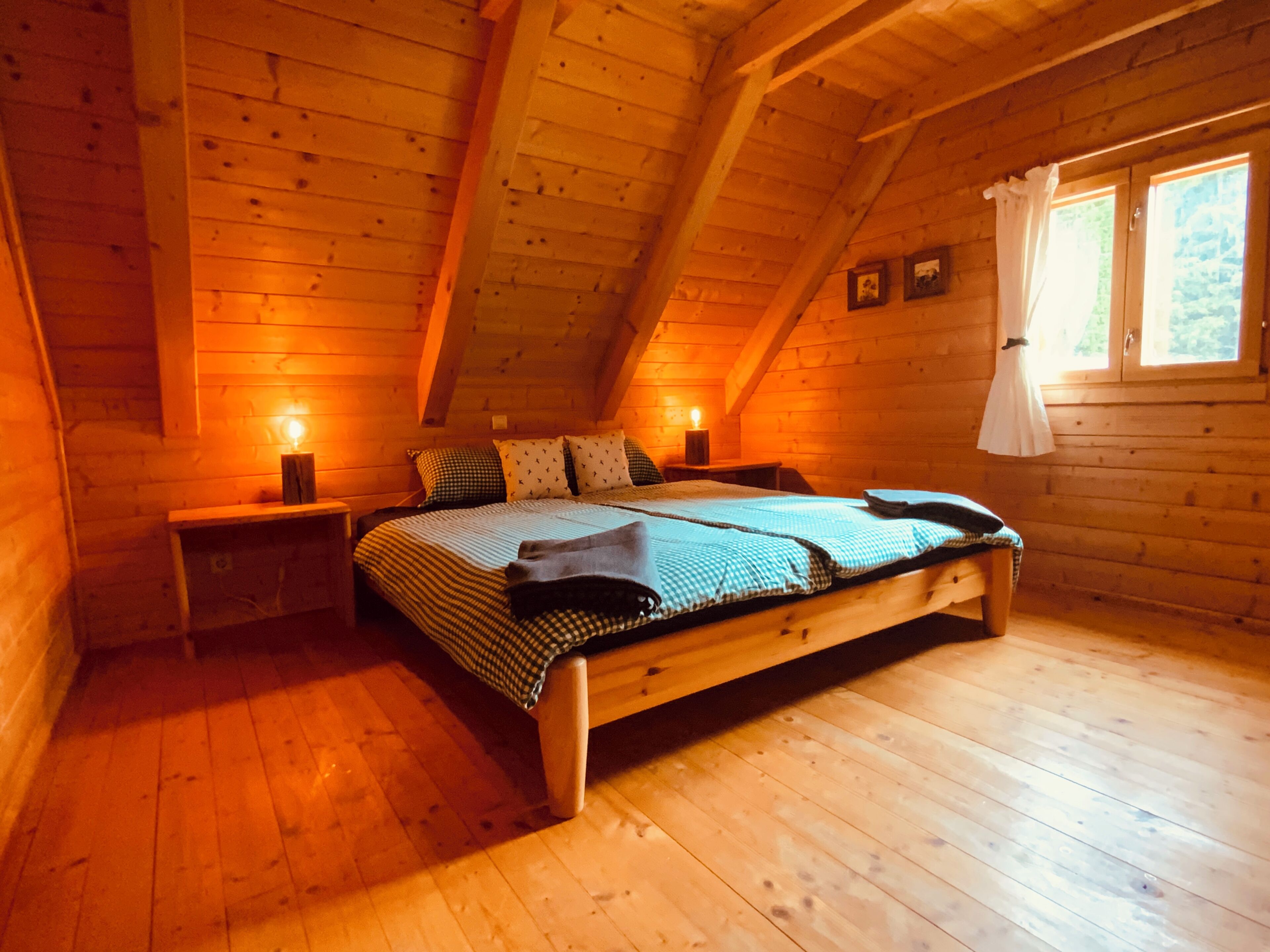 Een knus houten slaapkamer met een bed, nachtkastjes en een raam.