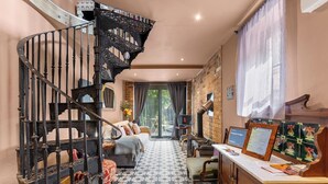 A staircase with ornate metal railings, a sofa, a table with a sign, and a patterned floor. - Keepers Lodge - Sleeps 4 (Nottingham)